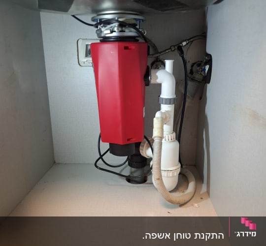 מתקן אדום מתחת לכיור עם צינורות חיבור